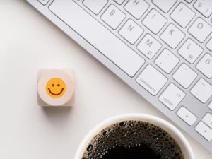 Auschnitt einer Apple-Tastatur und eines Kaffees; Holzwürfel mit Smiley